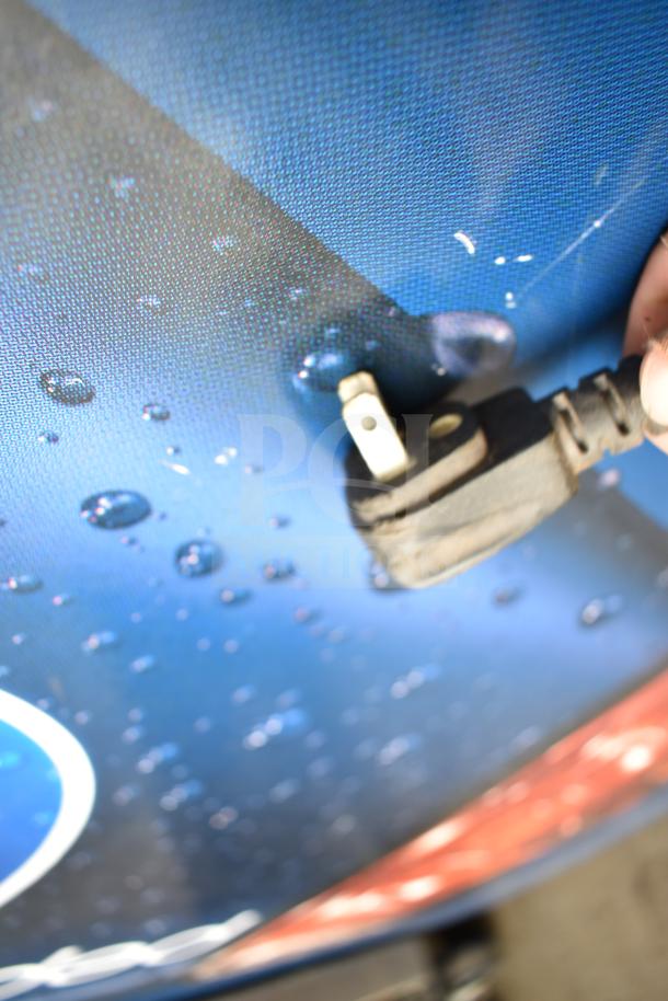 Electrical plug of QBD DC26HB cooler against a textured, water-patterned surface.