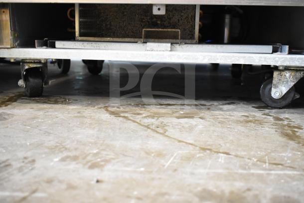 Coldline C-1FE commercial freezer base with pan rack on casters, 115V, 1 phase. Visible are sturdy wheels and metal framework.