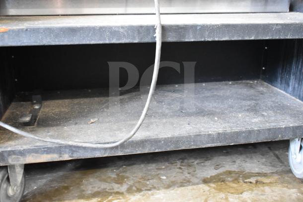 Vulcan 1013776 bakery merchandiser on commercial casters, used condition, black shelving, visible wear and dust.