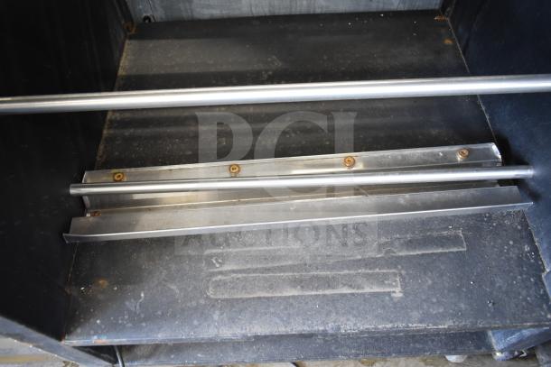 Vulcan 1013776 commercial pastry bagel merchandiser with metal rods, on casters, showing interior and signs of use.