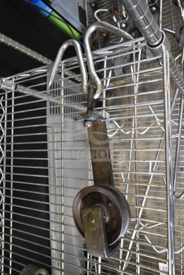 Vintage trolley roller on metal grid, featuring a rusted wheel and hook. Industrial design, functional, durable.