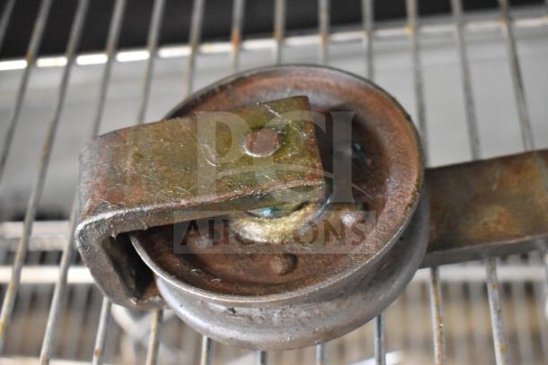 Heavy-duty metal trolley roller with visible wear, solid construction, and rust patina. Auction includes five rollers.