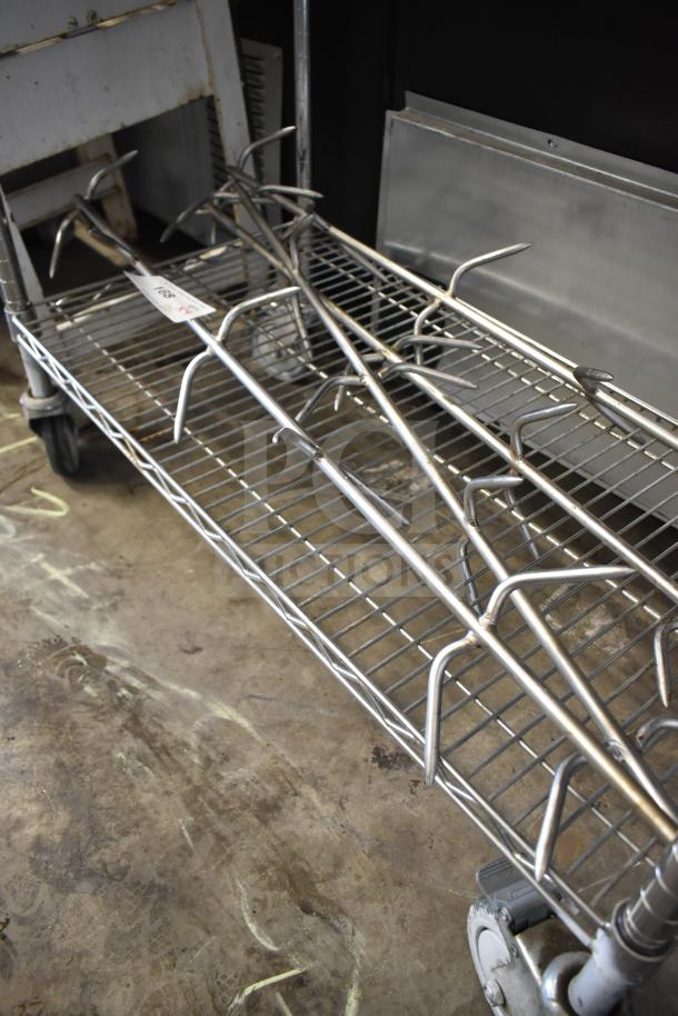 4 stainless steel rotisserie oven skewers on a wire cart, suitable for commercial use; minor wear visible.