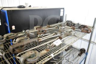 15 industrial trolley rollers on metal shelving, used, various conditions. Auction tag reading "169" visible.