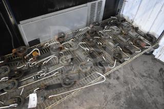 24 trolley rollers and hook meat hangers on a wire rack in used condition. Includes tag number 171.