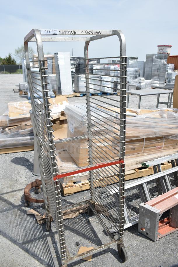 Commercial pan transport rack on casters with metal frame, multiple shelves, marked "KSTONE CATERING," showing some wear.