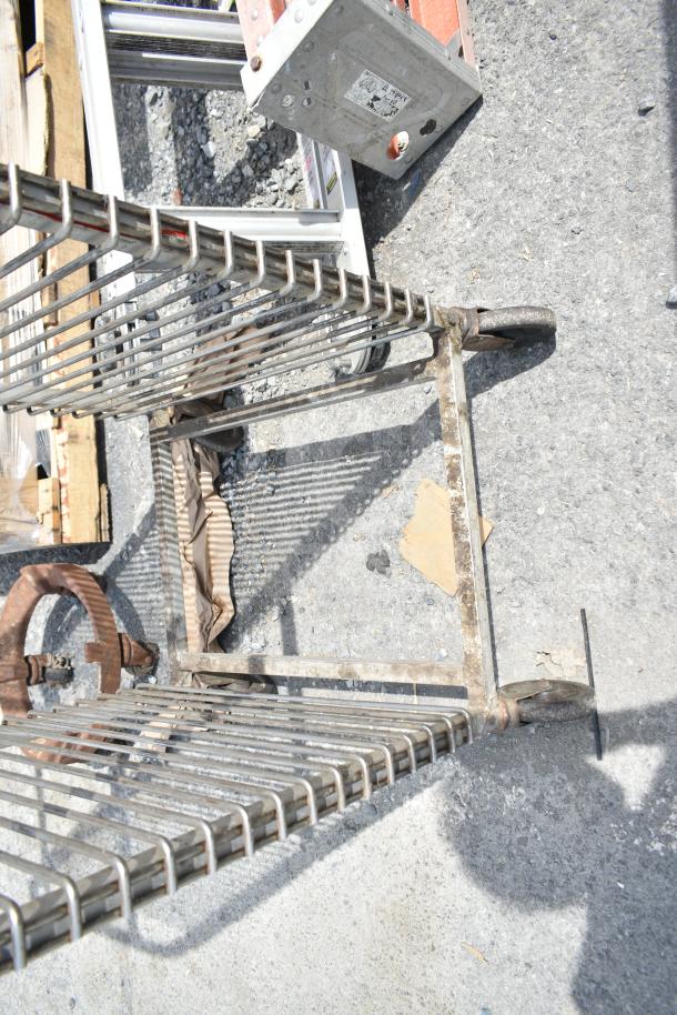 Commercial pan transport rack with durable metal frame on caster wheels, showing signs of wear.