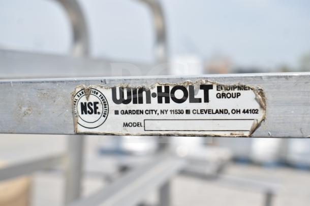 Win-Holt commercial pan transport rack with NSF label, sturdy design, on casters for mobility. Visible wear on the label.