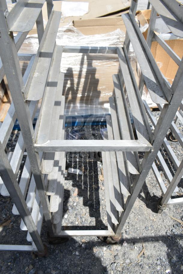 3 commercial pan transport racks on casters, metal structure, fair condition, outdoor setting. Ideal for kitchen use.