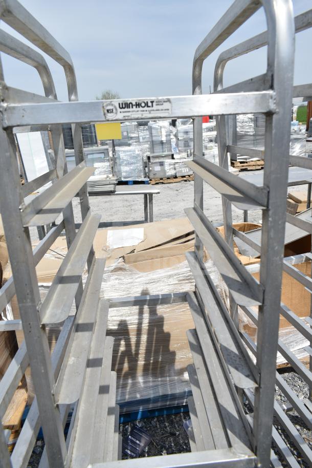Three Win-Holt commercial pan transport racks with casters, aluminum frame, outdoor setting, good condition, visible label.