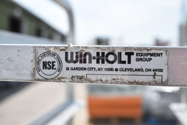 Commercial pan transport rack with Win-Holt branding. Features NSF certification, commercial casters, visible wear on label.