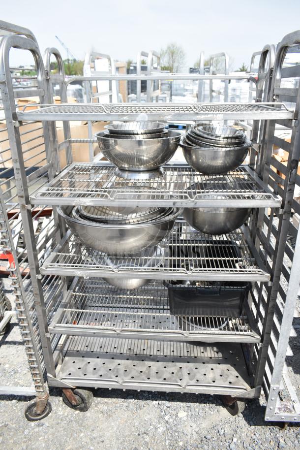Commercial transport rack on casters with metal wire shelves, containing stacked metal bowls. Good condition.