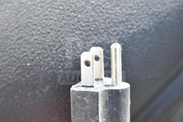 Close-up of a power plug for Kobalt 0241568 Concrete Mixer, highlighting its connector prongs against a textured background.