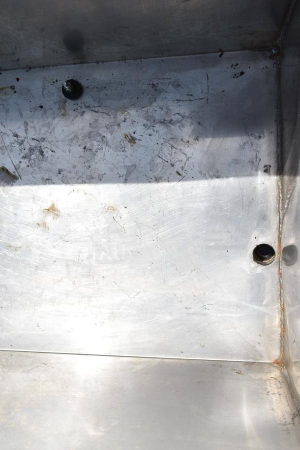 Commercial portable bin with metal interior, visible wear, and commercial casters, designed for industrial use.