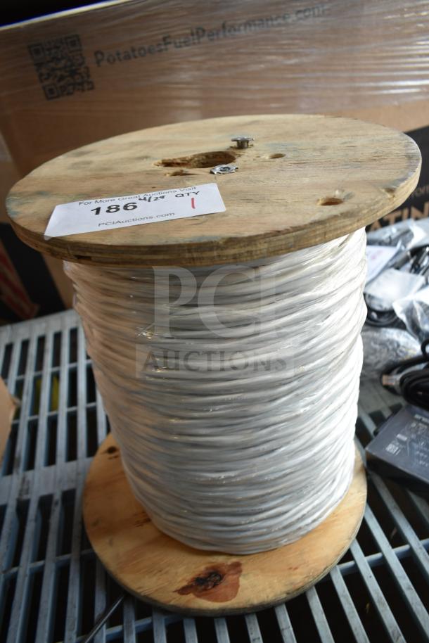 Wooden spool with white cable, tag labeled "186," indicating auction number and quantity. Good condition.