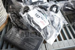 10 various items including an AC adapter and cables in sealed bags, labeled "187 QTY VX10" for auction.