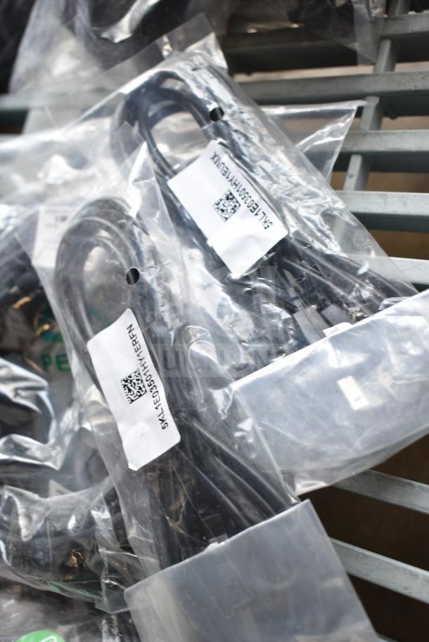 Assorted electronics lot including AC adapter and cables, sealed in plastic with labeled barcodes, for auction.