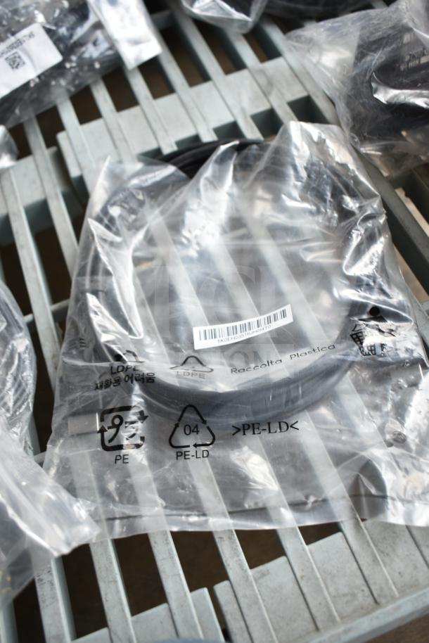 Plastic bag containing various cables, including an AC adapter. Packaging shows recycling symbols and a barcode label.
