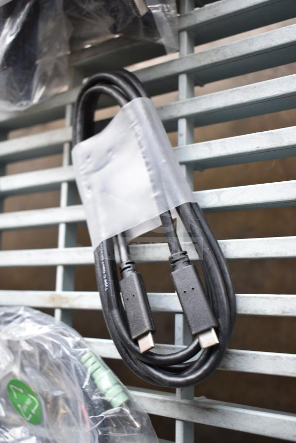 Various electronic cables, including USB-C type, bundled in plastic with visible markings, in new condition.