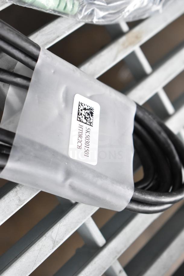 Bundle of various items including AC adapter and cables, labeled with code 5K50301501 HTR02CB. Coiled, unused condition.