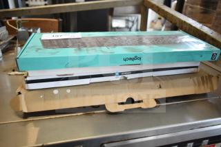 Stack of four brand new keyboards in boxes, including Logitech and Onn models. Boxes show minor scratches and dents.