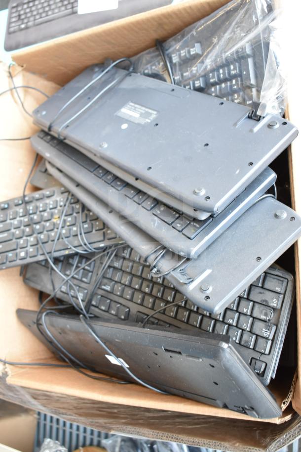 Pallet lot of various wired keyboards piled in a box, mixed condition, ideal for bulk purchase.