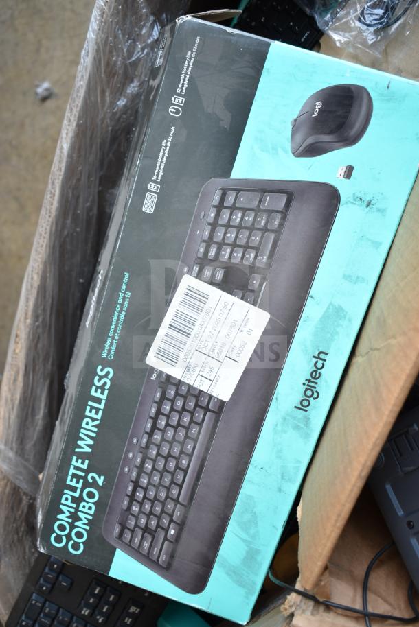 Boxed Logitech Complete Wireless Combo 2 on a pallet, part of a mixed keyboard lot for auction. Visible product label and barcode sticker.