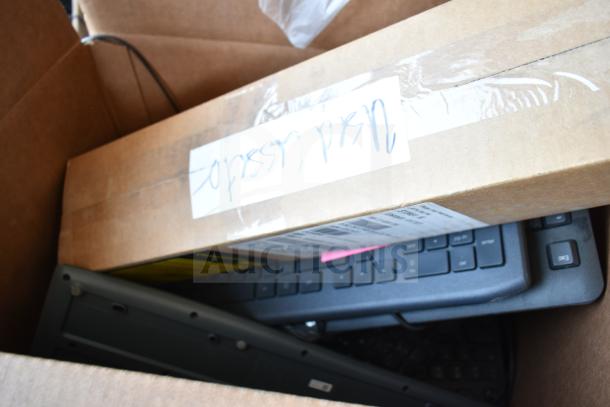 Pallet lot of various keyboards in cardboard box, mixed conditions. Some labels visible, indicating assorted makes and models.