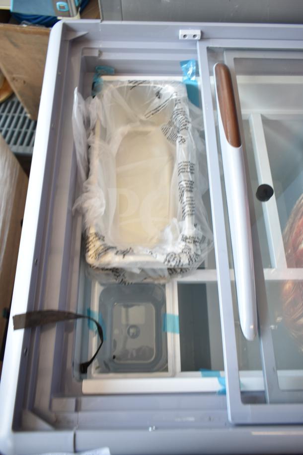 Brand new KoolMore KM-GDC-26SD gelato display freezer, 5-pan, sliding glass door, on casters, 6 cu. ft., some visible packaging.