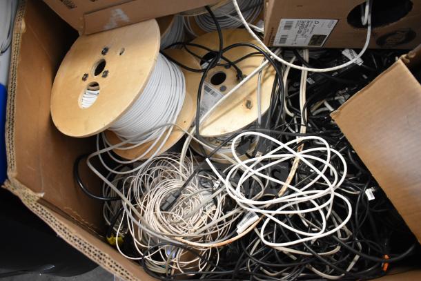 Pallet of GenSpeed Cat 5e riser cables on wooden spools, mixed colors, various conditions, in cardboard boxes.