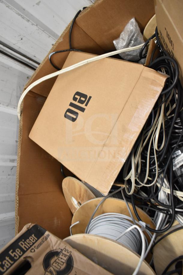 Pallet of GenSpeed Cat 5e Riser Cables, assorted colors on wooden spools and cardboard boxes. Suitable for networking use.