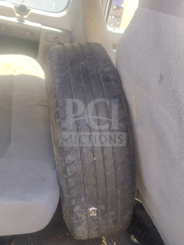 Interior of 2010 Ford E350 Cargo Van showing spare tire leaning against a seat. Odometer at 162,472 miles, clear title available.