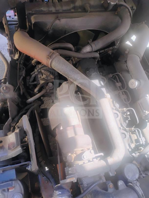 Engine compartment of a 1998 UD International Cab-Over Refrigerated Box Truck. Clearly visible pipes and engine components.