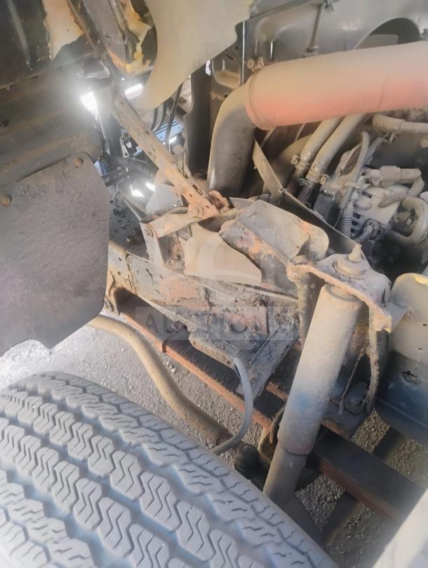 Close-up of the undercarriage of a 1998 UD International Cab-Over Refrigerated Box Truck, showing its suspension and wheel area. Condition shows wear typical of a used vehicle.