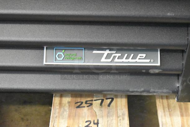 True FLM-81 Commercial 3-Door Reach-In Cooler, black finish with "natural refrigerant" label, new with minor scratches.
