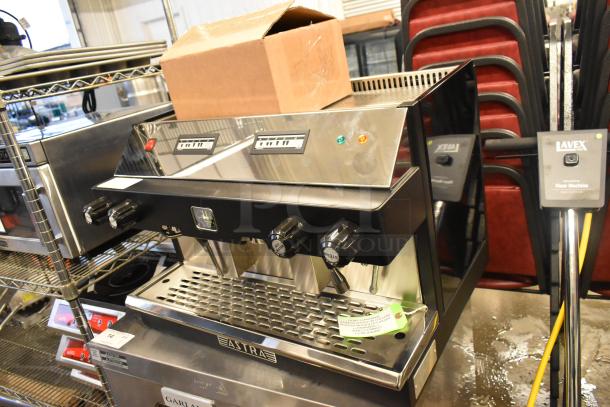 Brand new Astra M2 012 stainless steel espresso machine, 2 group, 220V, with minor scratches and dents, on display.