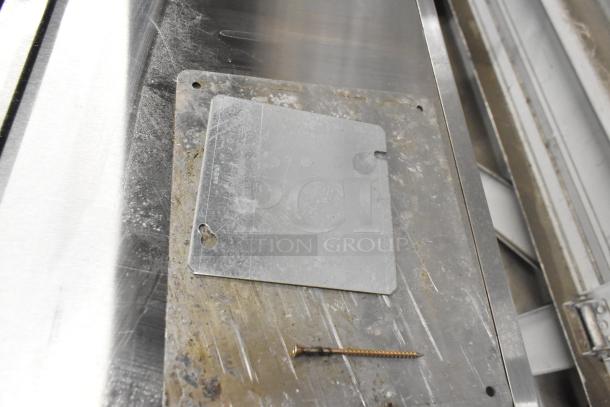 Metal plate on a stainless steel surface, showing signs of wear.