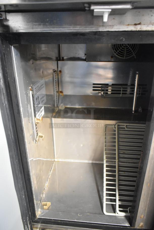 Turbo Air MUF-36-N stainless steel undercounter freezer interior, includes shelving, showing minor wear. Model and voltage label visible.