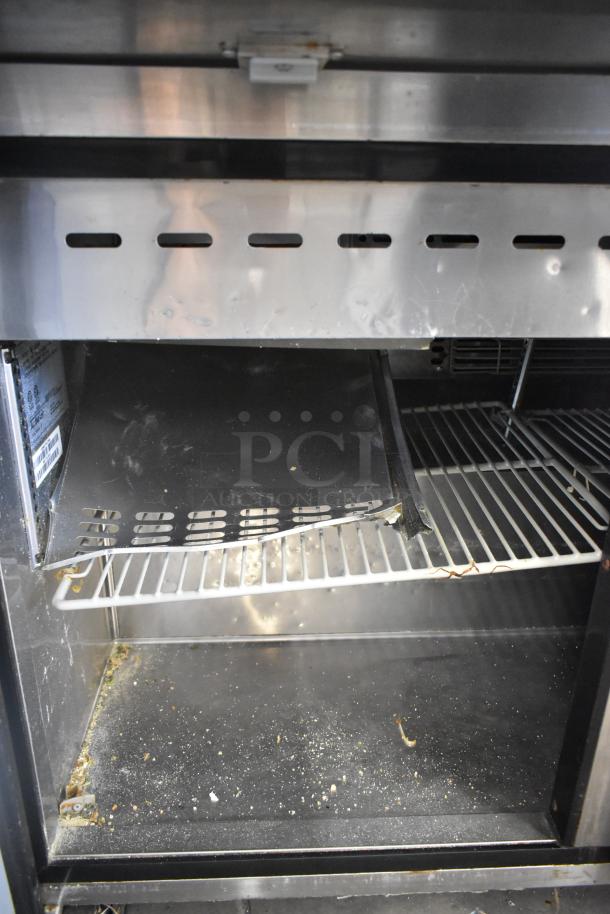 Turbo Air MST-72-30-N stainless prep table interior; shows shelves, light wear and debris. 115 volts, 1 phase, commercial use.