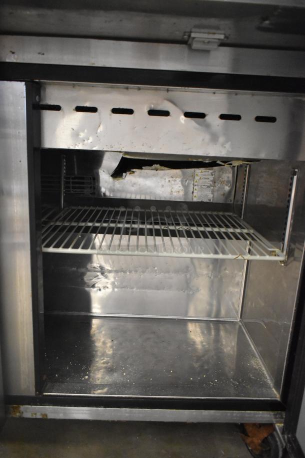 Turbo Air MST-72-30-N commercial prep table, stainless steel, visible interior wear, shelving, 115 Volts, on casters.