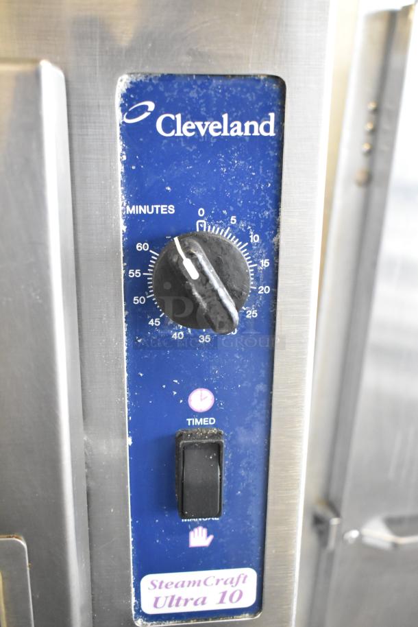Cleveland SteamCraft Ultra 10 control panel with timer dial, button labels, and visible wear on stainless steel commercial steam cabinet.