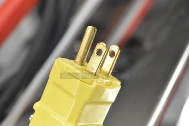 Yellow power plug of a 2024 Pavoni Newcookmatic V1 pastry press, showing three prongs, indicating 110 volts, 1 phase.