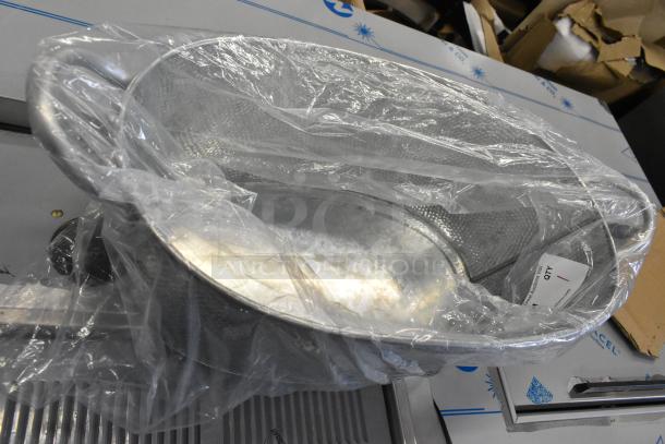 Brand new metal ice bucket wrapped in plastic, showing minor scratches and dents. Features handles and a textured surface.