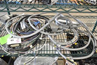Lot of various wires and cables on metal shelf, some labeled with tags. Includes power connectors and braided cables.