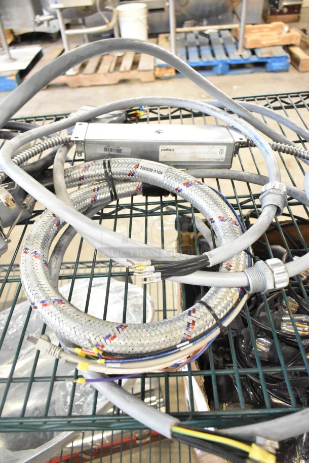 Lot of various wires and cables on a metal rack, including a braided wire labeled "220928-1104" with connectors.