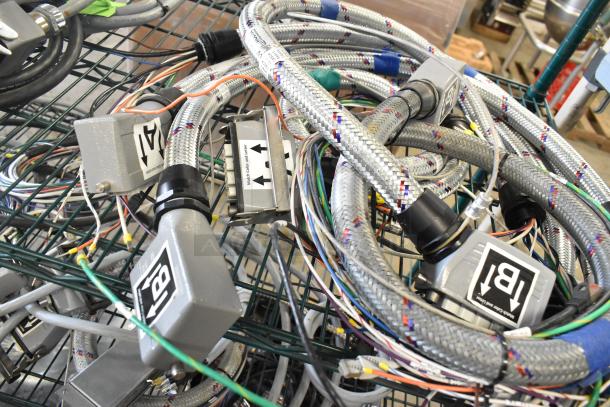 Assorted wires and cables, including braided and labeled ones, in a metal basket. Various connectors visible, in good condition.