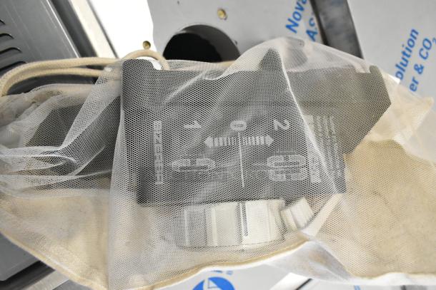 New Bizerba Meat Slicer Blade Sharpener, partially visible in protective mesh, showing controls and dial markings.