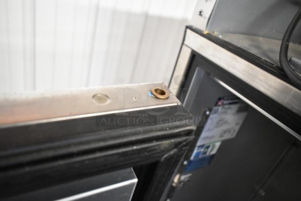 2024 True TG2R-2S-HC stainless steel cooler, door detached, visible wear. Poly coated racks inside. Model and specs label visible.