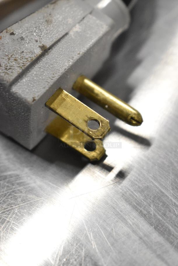 Close-up of a power plug for a True TUC-24F-HC undercounter freezer, showing two flat blades and a round grounding pin.