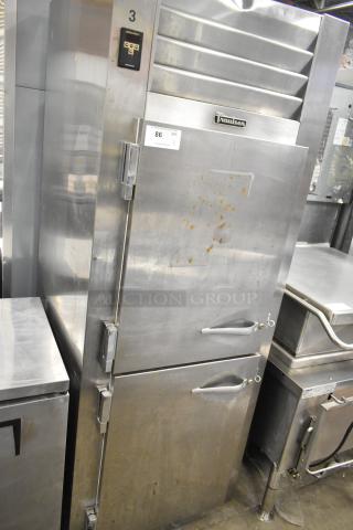 Traulsen stainless steel commercial cooler with two half-size doors and metal racks. 115 volts, 1 phase, visible wear.